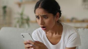 retrato muçulmano islâmico indiano mulher árabe menina fêmea senhora lendo mau notícia rejeitar recusar conectados perdido perder às casa olhando às Smartphone Móvel telefone Internet problema problema chateado triste frustrado video