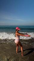 uma mulher alegremente desfrutando a refrescante ondas às a de praia debaixo a brilhante verão brilho do sol video