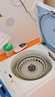 moderno aparelho para verificação amostras dentro laboratório. mão dentro azul luva coloca plástico tubos com sangue testes para orifícios do centrífuga. vertical video