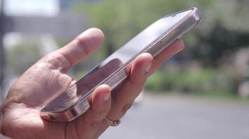 un persona es utilizando un teléfono inteligente en un bullicioso ciudad lleno con actividad y carros video