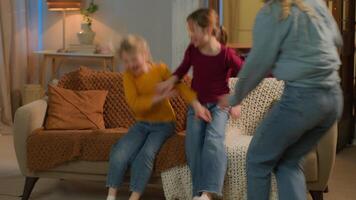 contento caucasico famiglia poco bambini ragazze fratelli figlie madre padre raccogliere insieme casa sera fine settimana divertente spensierato bambini genitori mamma papà salto su divano divano bonding avere divertimento in movimento giorno video