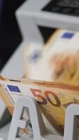 Orange billets de banque de cinquante euro tournant rapidement dans en espèces compte machine. Nombres en changeant à le compteur dans se brouiller. proche en haut. verticale video