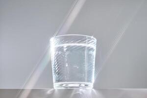 Glass of clean filtered water on white background with beautiful glare. photo
