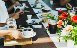 camarera servicio café bebidas a grupo de amigos reunión a cafetería. foto