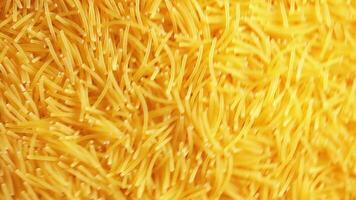 sfondo di crudo tagliatelle quello lentamente rotante senso orario - superiore Visualizza, angolare rotazione. struttura di asciutto vermicelli svolta intorno a. crudo pasta con Basso chiave leggero - giusto rotazione video