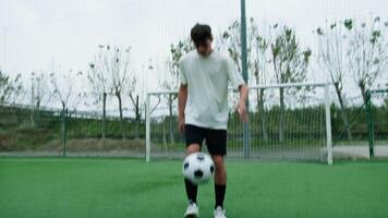 tiener dribbels met voetbal bal in de buurt de doel video