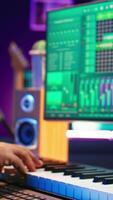 Vertical African american audio technician using piano synthesizer keys to add sound effects in post production, editing tunes with digital software and mixing console. Male artist in home studio. Camera B. video