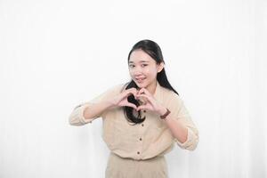 The expression of an Indonesian Asian model woman in white is smiling and making a love code photo