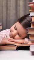 vertical cansado aluna pequeno menina pacificamente dorme em uma livro cercado de pilhas, simbolizando escola estresse. a imagem captura infância, aprendizado, e Saldo dentro Educação video
