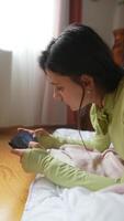 une Jeune femme est profondément engagé avec sa téléphone intelligent, confortablement situé dans sa confortable pièce video