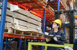 Two workers in a warehouse looking at a clipboard photo