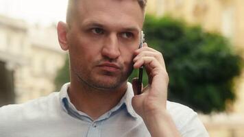 infastidito stressato pazzo caucasico uomo arrabbiato furioso uomo d'affari tipo turista all'aperto parlando smartphone conflitto litigare mobile Telefono conversazione negativo espressione scontento nervoso maschio chiamata nel città video