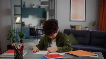 Tired stress African American 10s son boy child kid pupil schoolboy studying learning at home education writing task difficult homework write exercise study prepare exam test alone at table indoors video