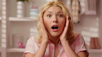 Happy excited smiling shocked surprised wonder amazed Caucasian woman girl female portrait face shock good news say wow holding head face open mouth big eyes in glamour pink candy bathroom at home video