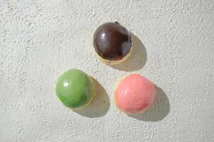 Tres diferente de colores rosquillas en un blanco superficie foto