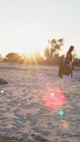 ragazza passeggiate e giochi il basso strumento su il spiaggia vicino il oceano a tramonto video