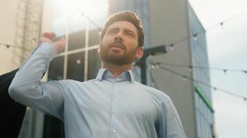 riuscito elegante sorridente fiducioso adulto caucasico uomo d'affari datore di lavoro anni 40 maschio attività commerciale di mezza età uomo Tenere formale giacca mettere su spalla stile moda opera ufficio edificio nel città sole leggero video