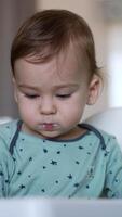 One year old baby boy sitting in a feeding chair eating from spoon. Lovely cute Caucasian child being fed from spoon by his mom. Close up. video