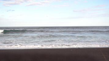 Rocky pacific ocean coast, sea wave crashing. Footage. Russia Kamchatka. Surfers wait for a wave in the distance. Marine background video