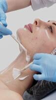Preparing for beauty treatments. Cosmetologist cleanses a woman face, creating a clean base for cream and anesthesia before starting skincare and rejuvenation procedures. Vertical shot video