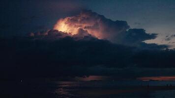 Flashes of lightning in a huge thundercloud that covers the evening sky. The moment of approach of a strong thunderstorm over the sea after sunset. The power of nature and the elements video