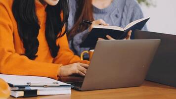 Two women sitting at a table with laptops video