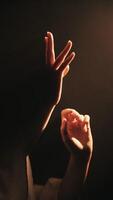 Hands reaching towards warm light in darkness video