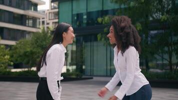 deux africain américain asiatique coréen femmes femme d'affaires affaires les partenaires collègues rencontrer donner haute cinq équipe la coopération Extérieur centre ville atteindre célébrer diverse ville collaboration collègues de travail femelles video