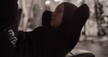 Muslim sportswoman doing abdominal crunches with hands behind head video