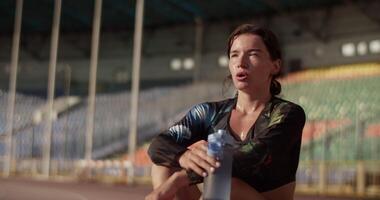 Sweaty sprinter drinking water after working out at stadium video