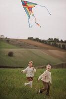 Carefree and laughing, Childs run through the meadow, their kite soaring like a bird. photo