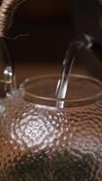 ein elegant Wasser Gießen in ein schön Glas Teekanne mit Anmut und Raffinesse. Medien video