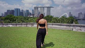 Woman walking towards Marina Bay Sands Singapore skyline video