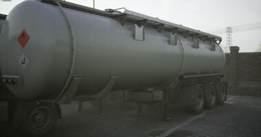 een groot grijs tanker vrachtauto staat nog altijd, geparkeerd in een mistig industrieel Oppervlakte video