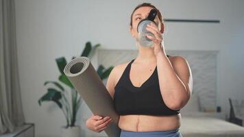 Yoga Fitness Sport trainieren Ausbildung. Frau halten Yoga Matte Trinken Flasche Wasser bereit zum üben Yoga Fitness beim heim. Plus Größe Mädchen im Sportbekleidung haben Ausbildung trainieren zum Gewicht Verlust Innen- video