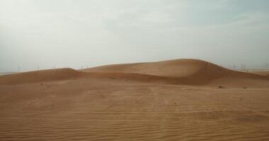 The wind inflates the sands of the desert, forming a beautiful sandy pattern. Desert sand dunes. Power lines in the background. 4k , red komodo video