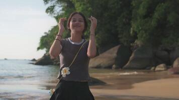 Happy adorable girl in casual dress relaxing on the beach under sunlight. Attractive carefree female teenager enjoy on the coastal area. Outdoor pursuit. video