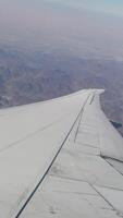 The wing of a passenger airliner against the background of mountain peaks on approach to Dubai airport video