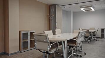 A modern meeting room in an office space with beige, calm tones in the interior. Office tables and chairs are present. No people in the scene. video