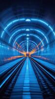 Brightly illuminated tunnel showcasing vibrant blue and orange lights along the railway tracks in an underground setting photo