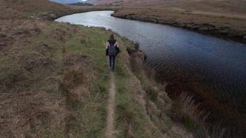 uno mujer mochilero excursionismo en sendero por el errante río cerca aesleagh caídas, condado mayonesa, Irlanda, aéreo, irlandesa paisaje, naturaleza y montañas video