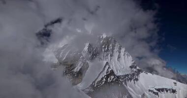 A drone flies through the clouds towards the snow-capped peak of a high mountain video