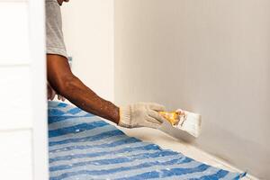 Painter hands with gloves painting the wall with brush. photo