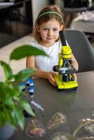 Portrait of little girl with green microscope. Concept of curiosity and early scientific exploration. High quality photo