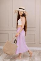 Woman in summer outfit with straw hat and jute bag, perfect for vacation, beach or boho fashion shoots. photo