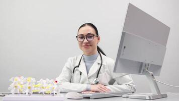 mulher médico ortopédico especialista trabalho dentro branco escritório usando uma computador. modelos do a joelho articulação, pélvico chão e pé estão em a mesa. publicidade do ortopédico diagnósticos. video