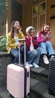 três à moda fêmea amigos estão partilha momentos antes uma período de férias viagem, ouvindo música e conectando com seus amigos com seus Smartphone. video
