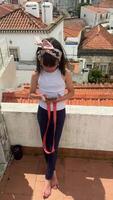 A Young Girl on a Rooftop Using a Smartphone Against a Beautiful Scenic City Background video