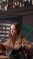 verticale femelle Université étudiant lit et écrit détaillé Remarques pour une Nouveau cours, en train d'étudier politique science pour A venir conférence dans une bibliothèque réglage à université. fille consulte base de données. caméra b. video