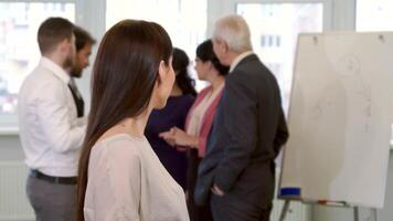 Confident businesswoman giving a thumbs up in a bustling office video